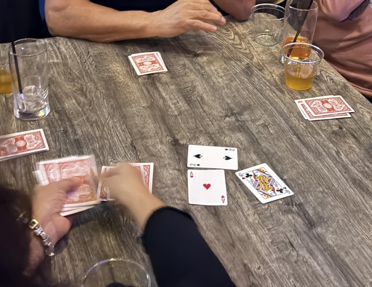 Manos repartiendo sobre la mesa, con las cartas jugadas a la vista